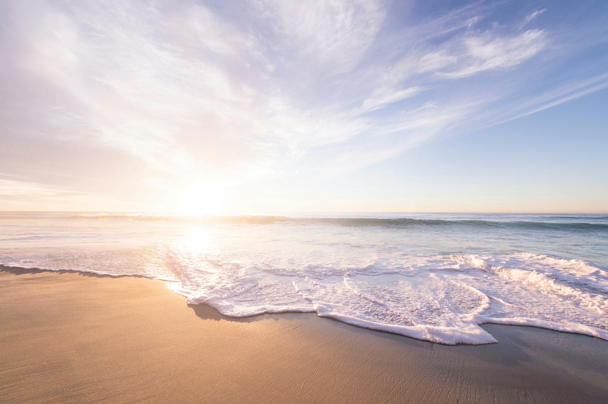 Sunlit waves washing over a sandy beach at golden hour